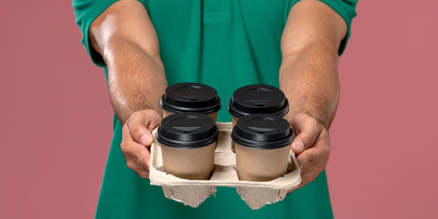front close view male courier green uniform holding coffee cups pink